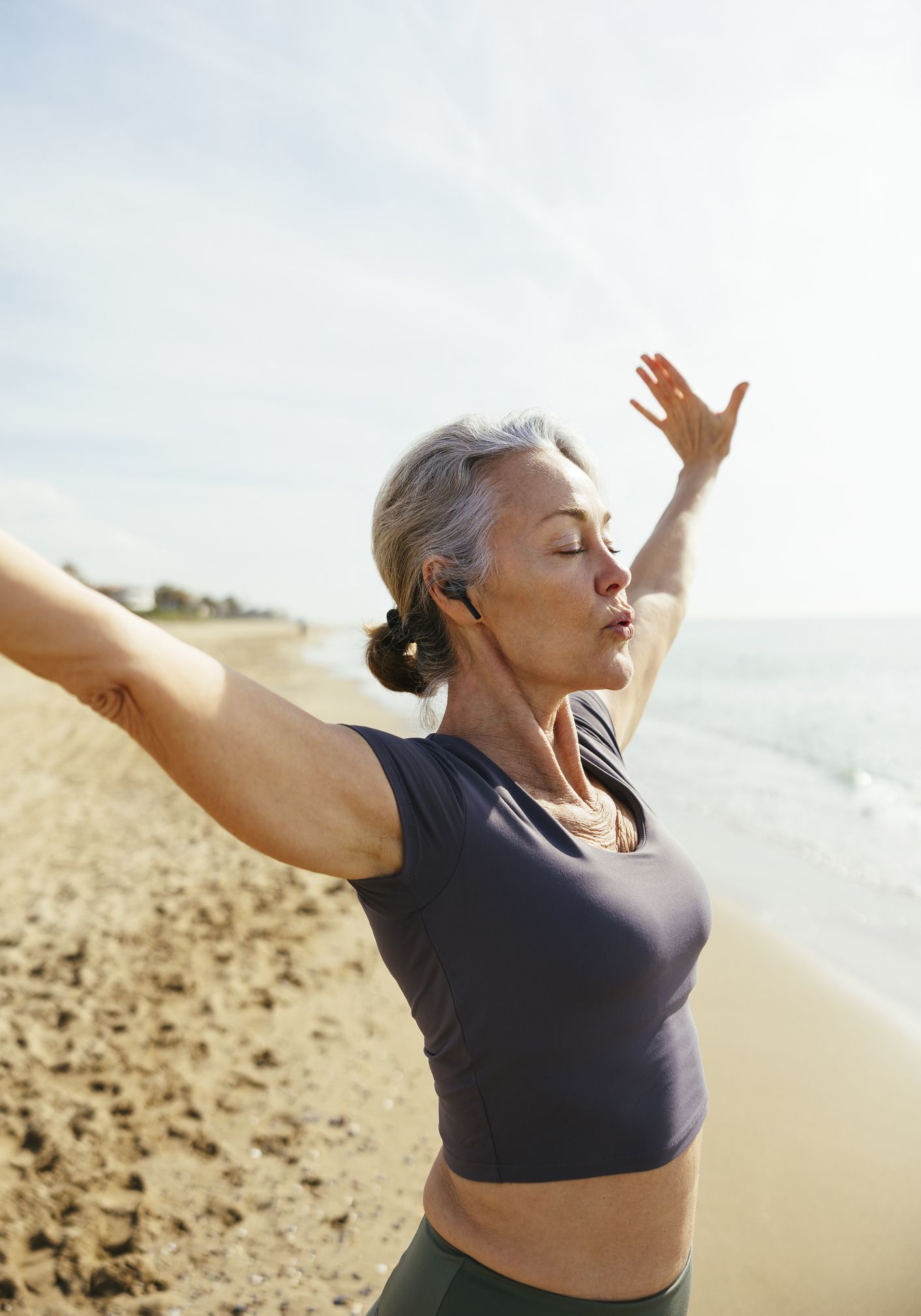 Frau mach Atemübungen am Strand - Longevity-Lifestyle