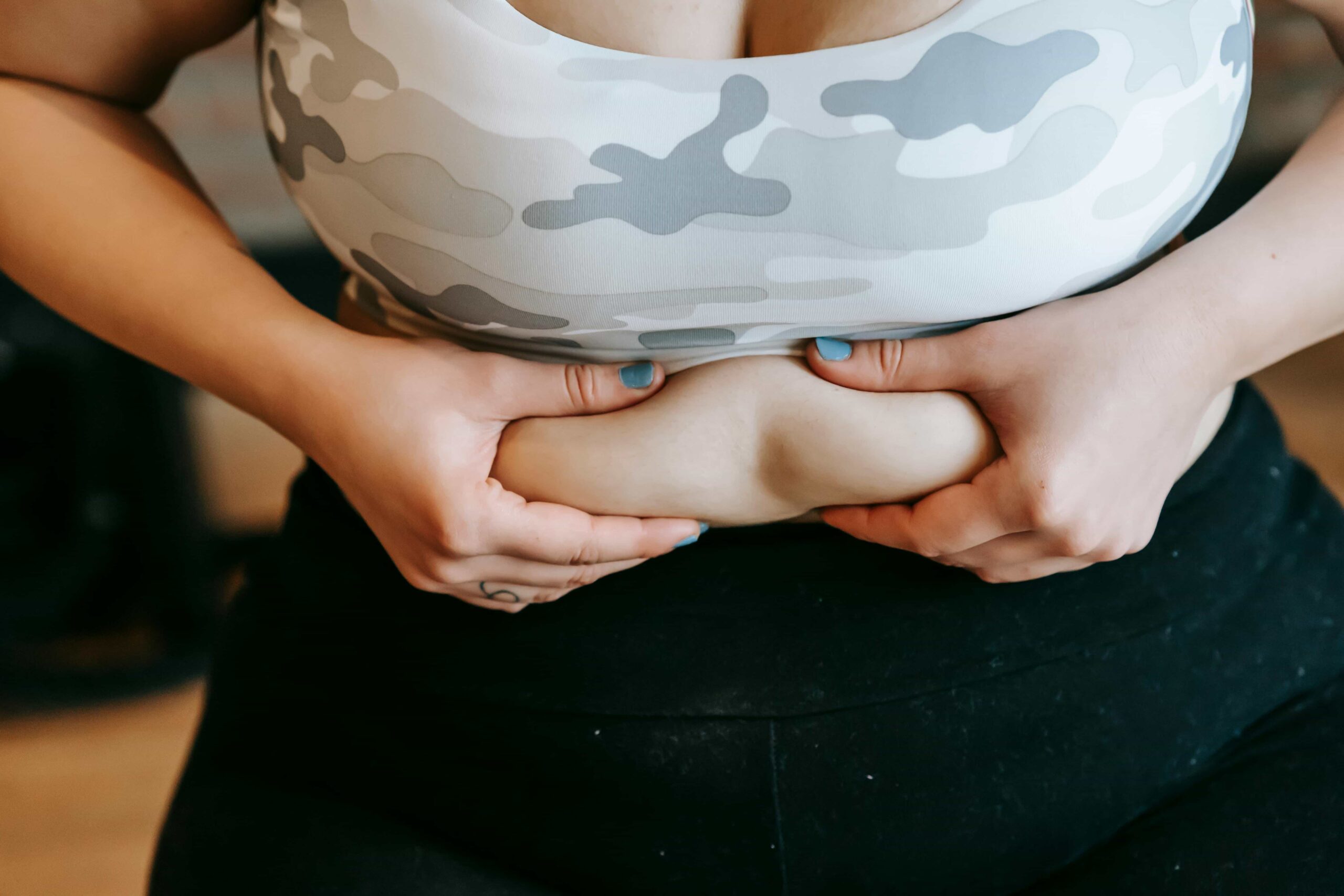 Ausschnitt aus einem Bild: Frau greift sich in ihre Speckrolle am Bauch