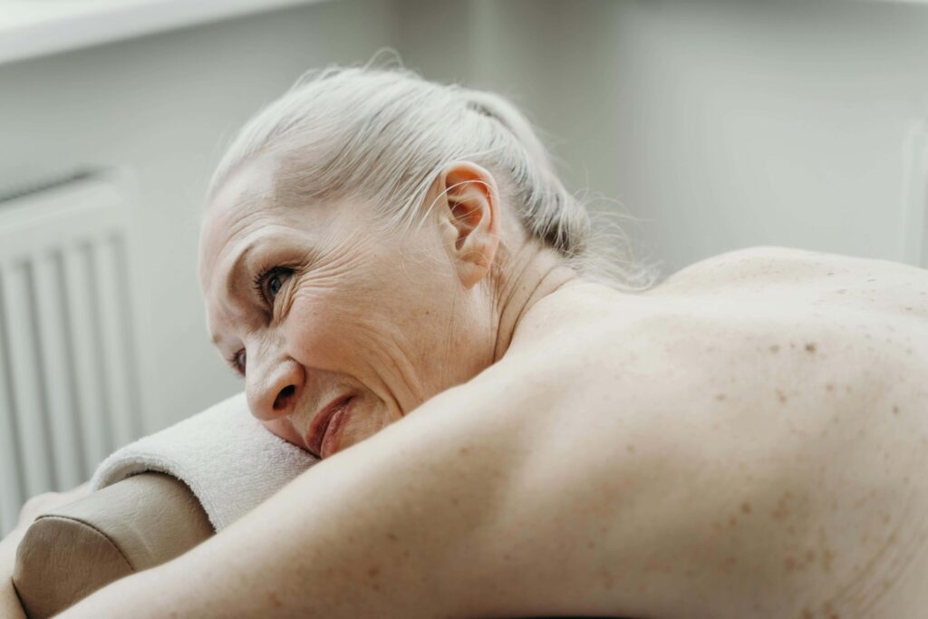 ältere Frau liegt mit nacktem Oberkörper auf einer Massageliege