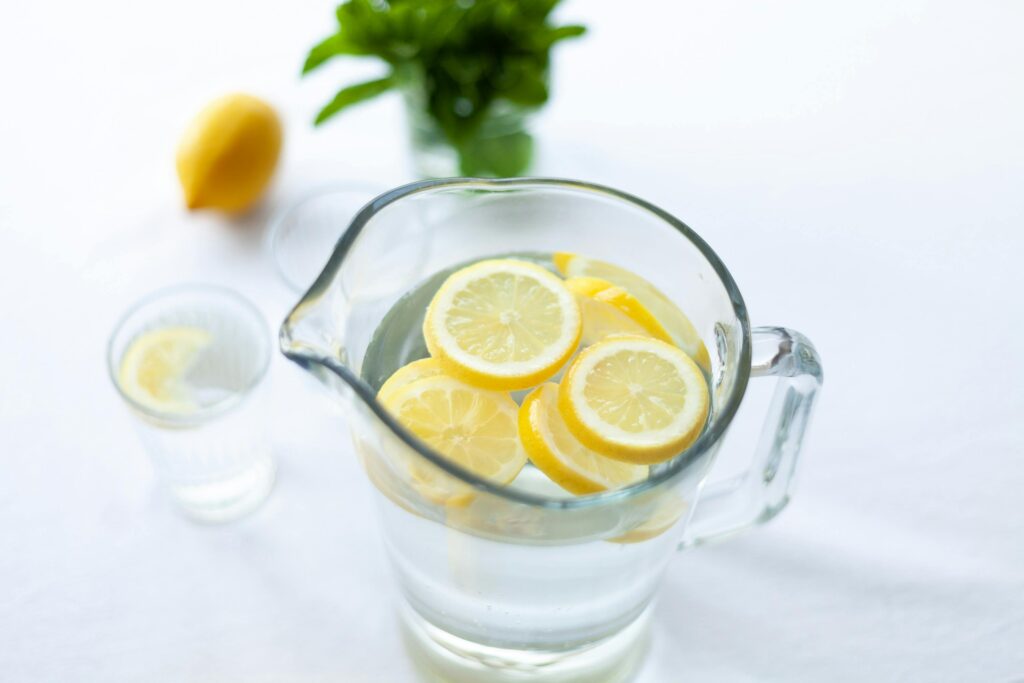 Eine Karaffe mit Wasser und Zitronenscheiben und ein gefülltes Glas - Ernährung & Longevity