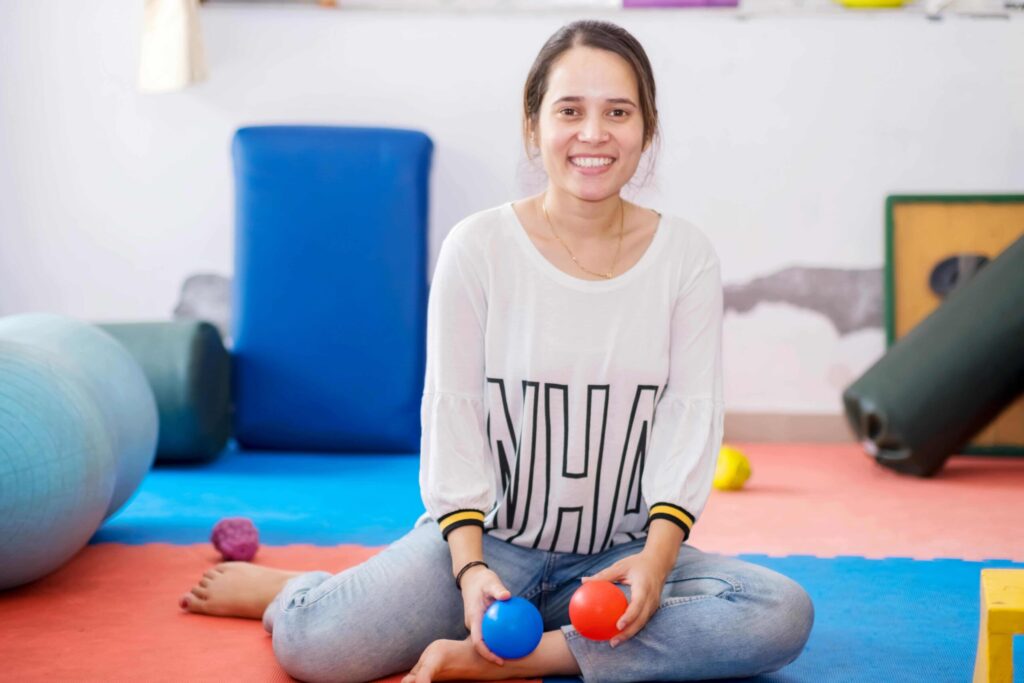 FRau sitzt auf dem Boden und hat verschiedene Trainingsgeräte für zuhause um sich verteilt - Fitness ab 50