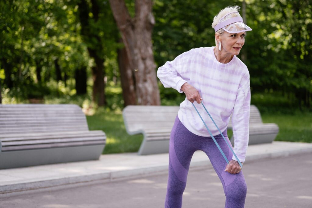 Frau trainiert mit Widerstandsbändern im Park - Fitness ab 50