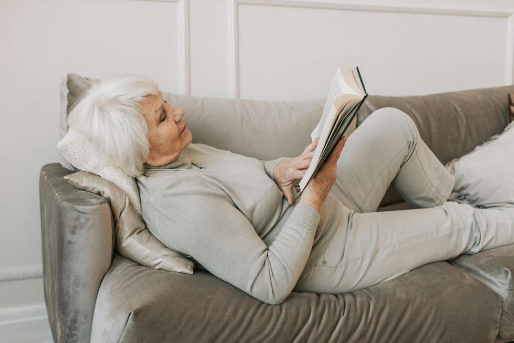 Frau liegt auf dem Sofa und liest ein Buch