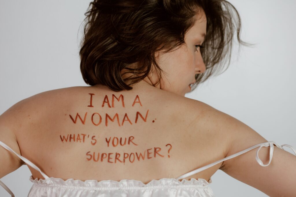 Frau zeigt ihren Rücken mit Text " I am a woman - what is your superpower
