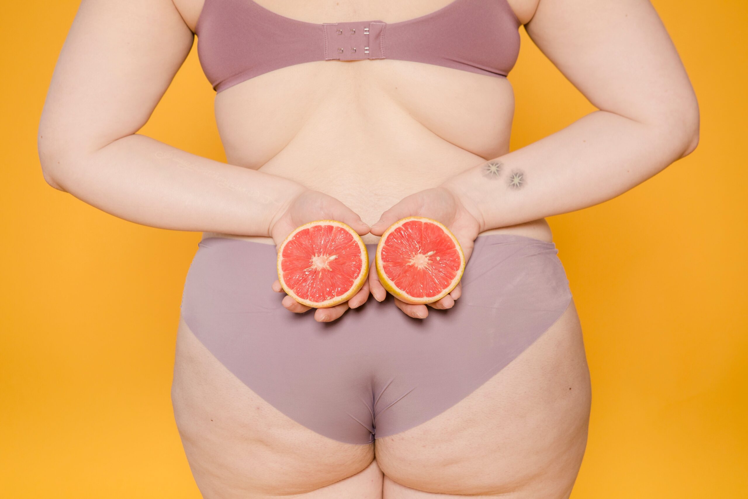 Frau mit Cellulite hat Orangen in der Hand