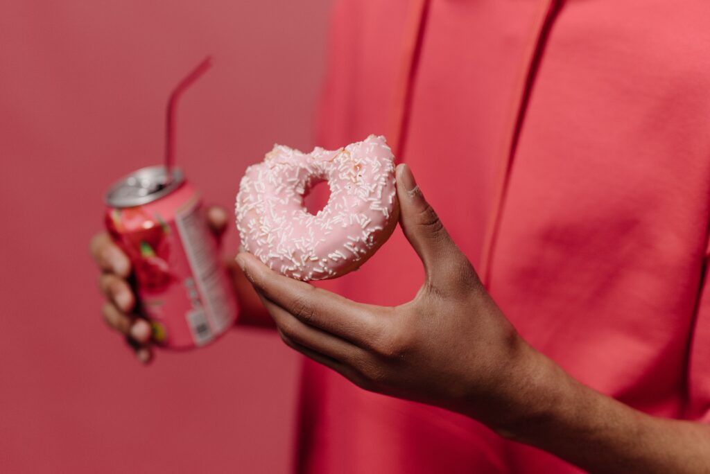 Frau hält Donut und Cola in der Hand