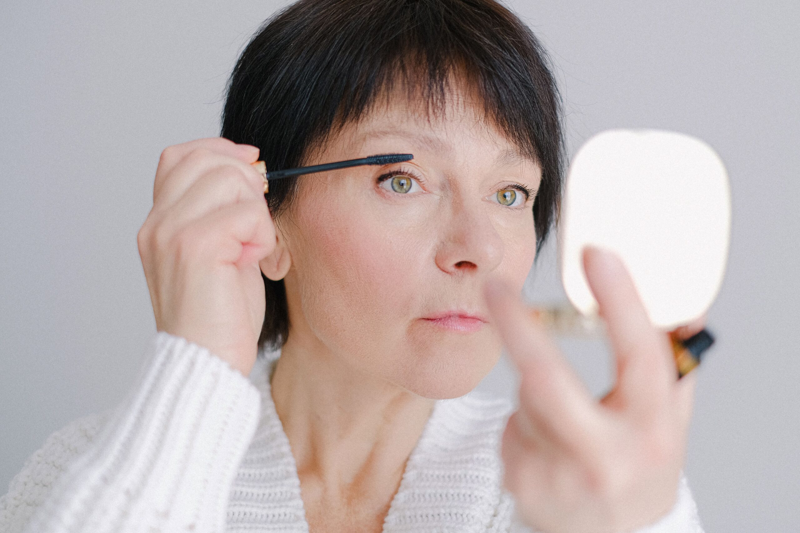 ältere Frau tuscht sich die Wimpern
